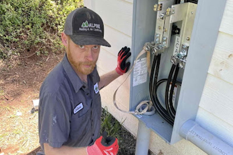 HVAC technician working on a home's electrical box outside.