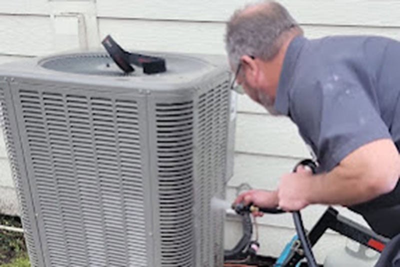 Alpine HVAC technician performing maintenance on a homes HVAC unit.