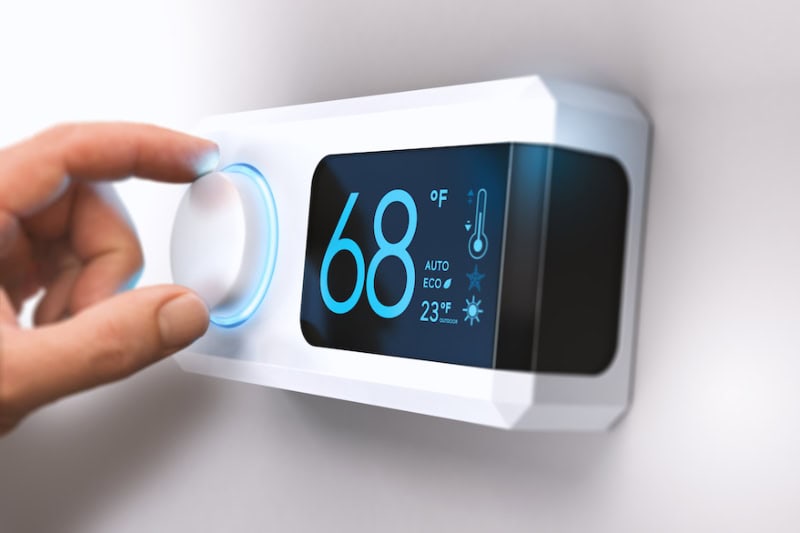 Hand on an air conditioning thermostat.