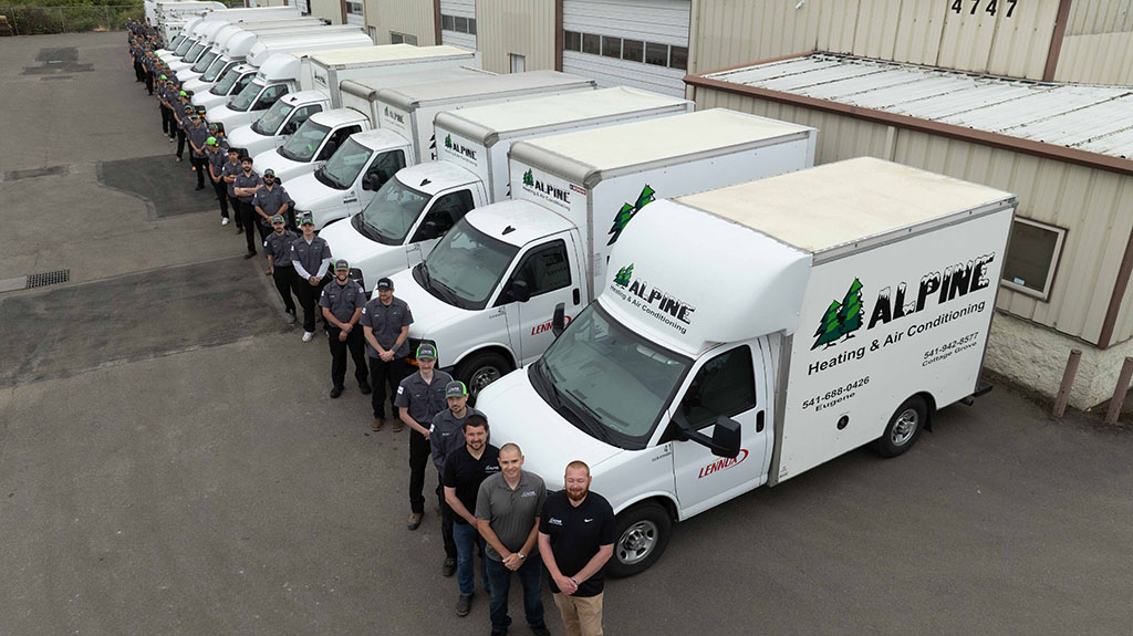 Alpine technicians lined up outside of their company vehicles.