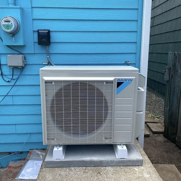 New Daikin air conditioner installed outside a blue home.