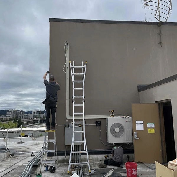 An HVAC technician in the process of installing a commercial hvac system on a roof.