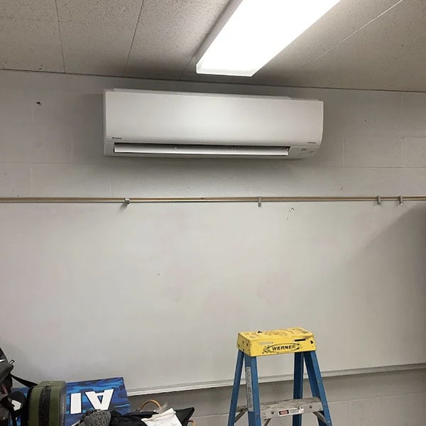 A ductless HVAC unit installed on the wall of a classroom.