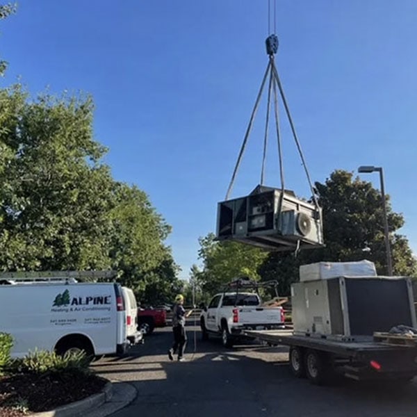 A crane lifting a commercial HVAC system onto a building.