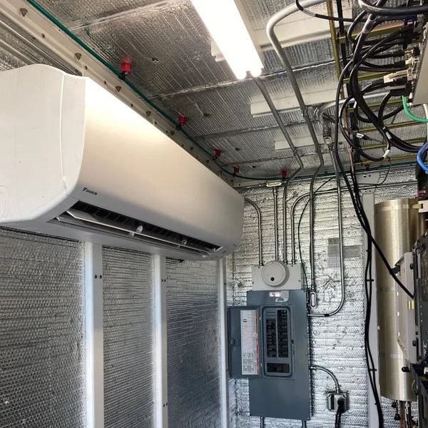 A ductless HVAC system on the wall of a small insulated room.