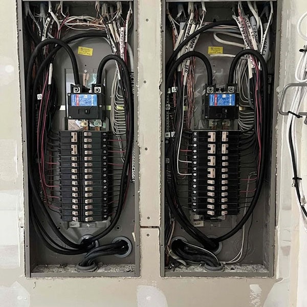 Two electrical panels on the wall next to one another.