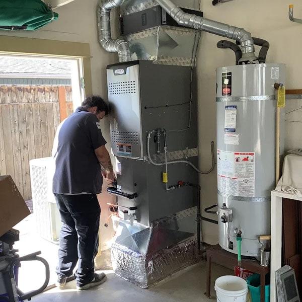 HVAC technician working on the furnace and AC system in a home.