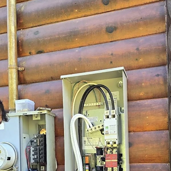 Electrical panel being worked on outside a home.