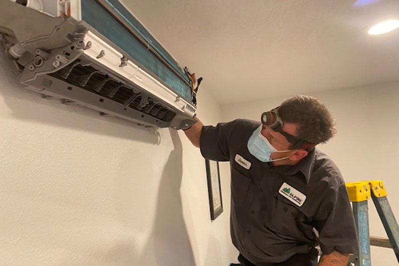 Alpine HVAC employee checking out a ductless unit in a home.