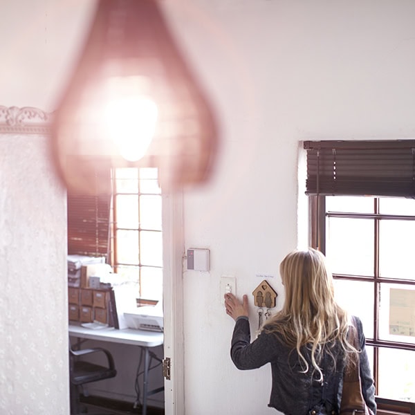 Woman flipping on a light switch in her home.